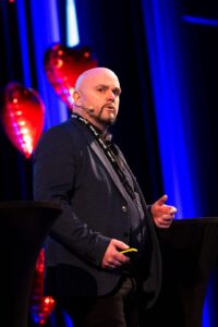 Mentor på konferanse med hjerteformede ballonger i bakgrunnen.