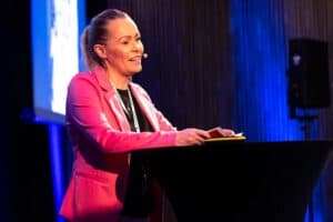 Kvinne holder tale på konferanse om byrom og fellesskap, inspirerende byromsdesign og samhandling.