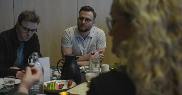Møte med tre personer rundt bord i byrommet, diskuterer planlegging og design.