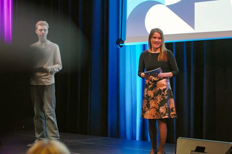 Hjerterom for byrom: kvinne holder presentasjon på scenen med stor skjerm bak seg.