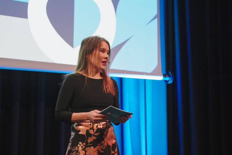 Kvinne holder presentasjon på scenen under Hjerterom for byrom arrangementet.