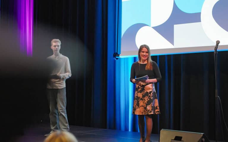To personer på scenen under Hjerterom for byrom arrangementet, en kvinne som snakker og en mann i ba.