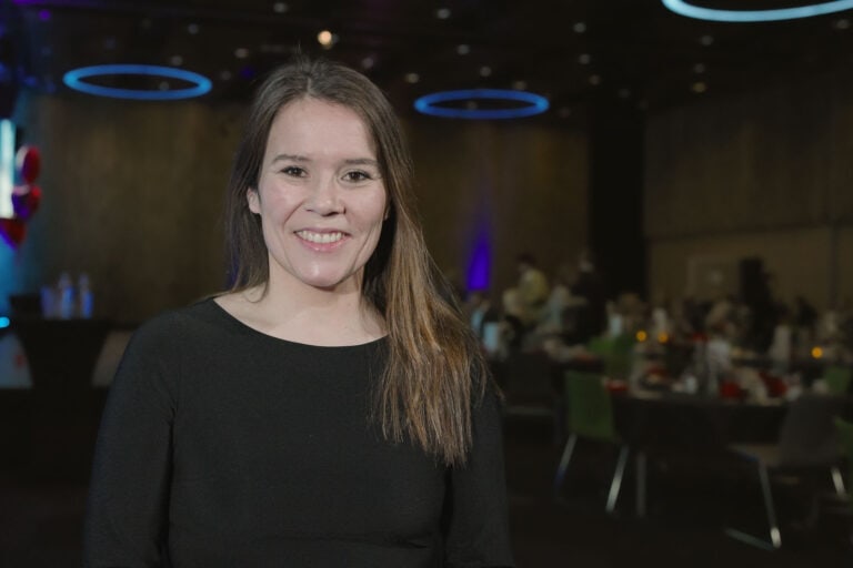Kvinne smilende på byrom-arrangement i innendørs lokaler.