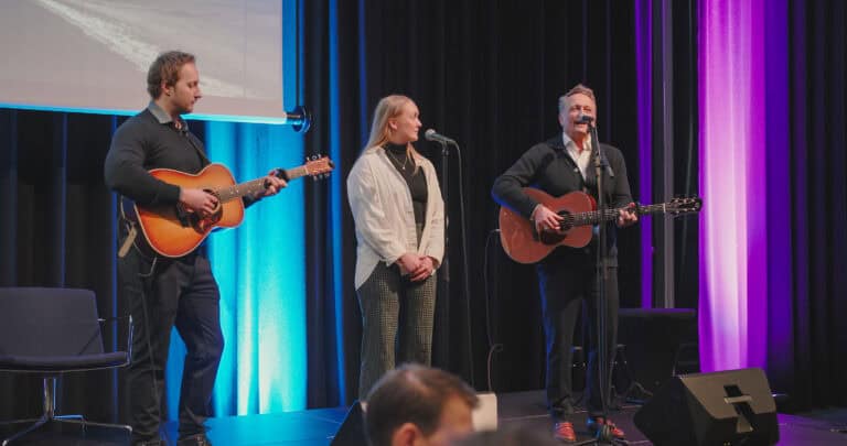 Tre artister fremfører akustisk musikk på scenen under Hjerterom for byrom.