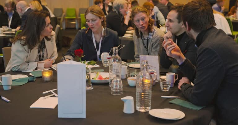 Gruppe mennesker i diskusjon rundt bord i Hjerterom for byrom.