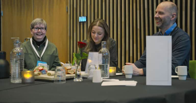 Møte i Hjerterom for byrom med tre personer som smiler og har samtale.