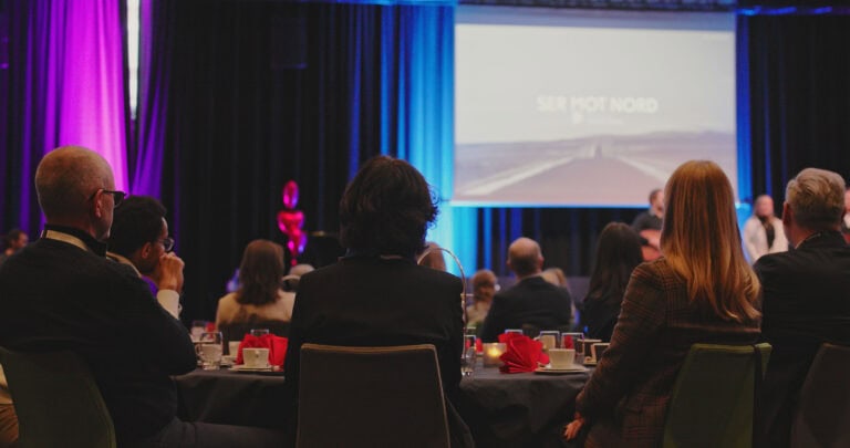 Publikum på konferanse i Hjerterom for byrom med presentasjon på skjerm.