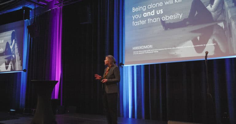 Person som holder foredrag på scenen med presentasjon om mental helse og selvstendighet.