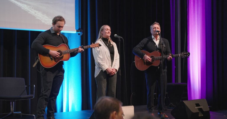 Tre musikere opptrer på scenen under Hjerterom for byrom arrangement.