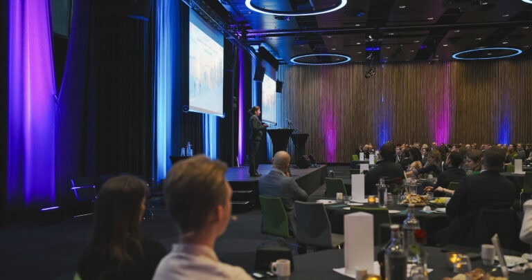 Profesjonell konferanse med presentasjon i stort auditorium, fullt av deltakere og moderne utstyr.