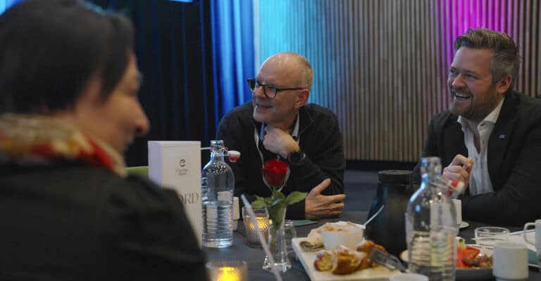 Møte mellom tre personer i Hjerterom for byrom, smilende og engasjerte.